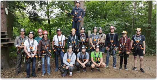 Gruppenfoto zeigt GreenGate Mitarbeiter in Klettermontur in einem Kletterwald.